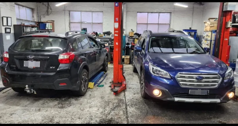 An SUV and a sedan in the workshop awaiting roadworthy inspection